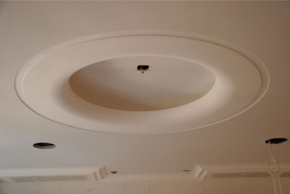 Ceiling with recessed oval tray, central light fixture, and exposed wiring holes