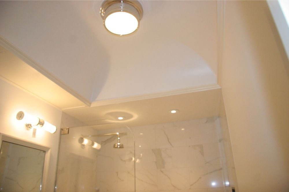 Ceiling light and mirrored bathroom wall with vanity lights and tiled shower area
