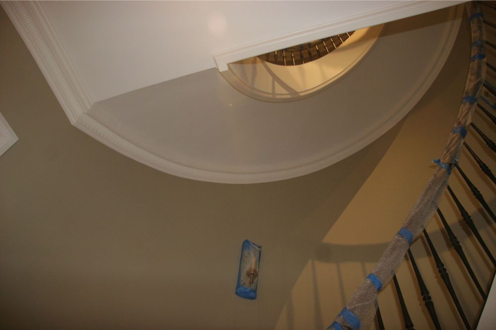 Spiral staircase with curved beige wall and a hanging blue object viewed from below