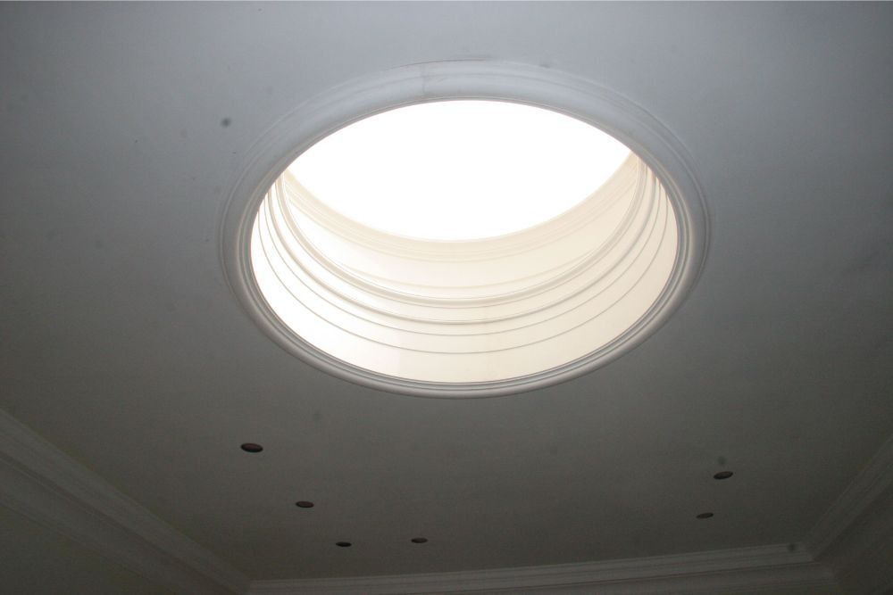 Ceiling skylight with bright circular opening in a white room