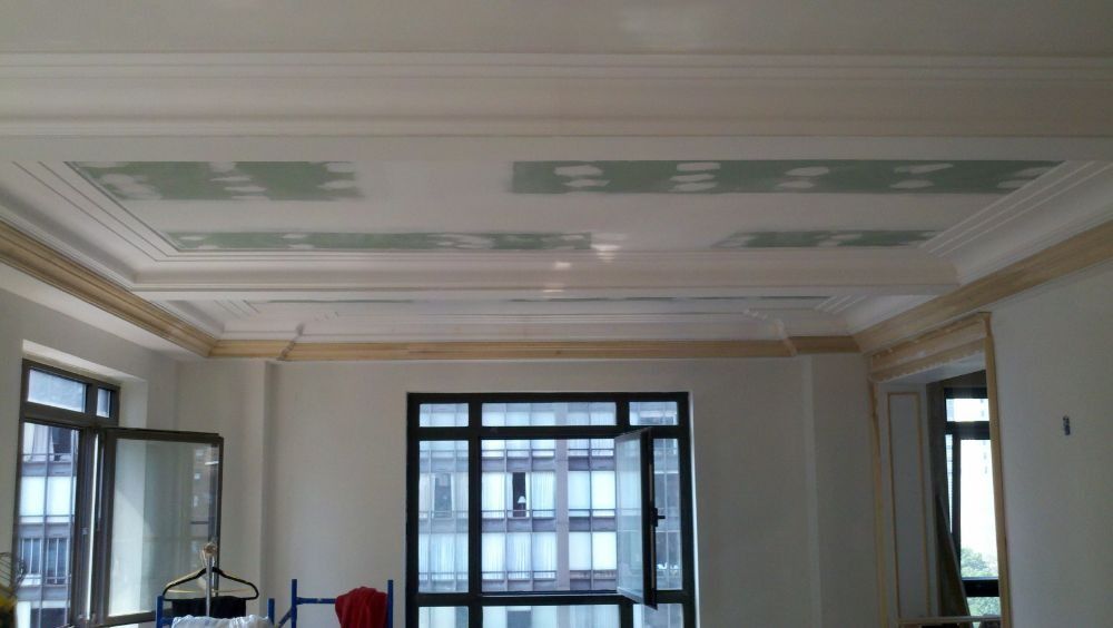 Bright room with decorative ceiling moldings, large windows, and neutral walls.