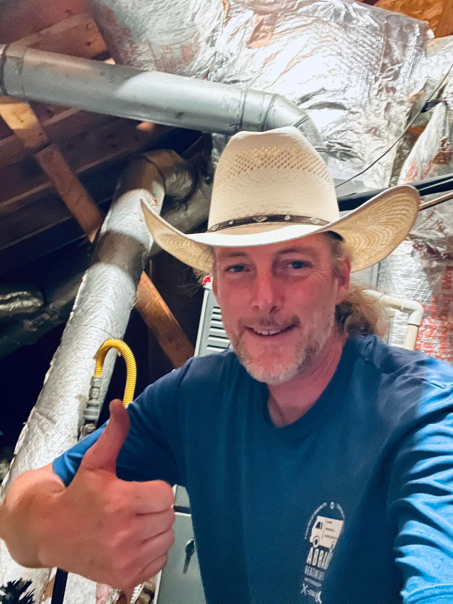 A man wearing a cowboy hat is giving a thumbs up.