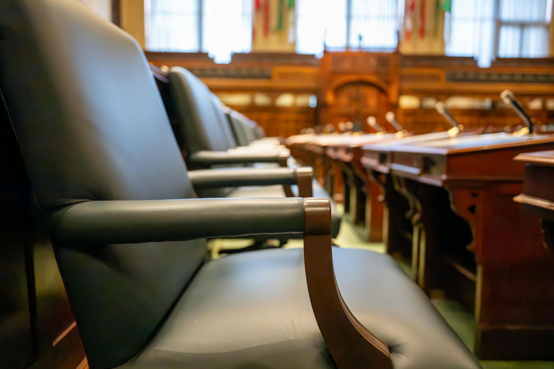 A row of empty chairs in a courtroom with microphones.