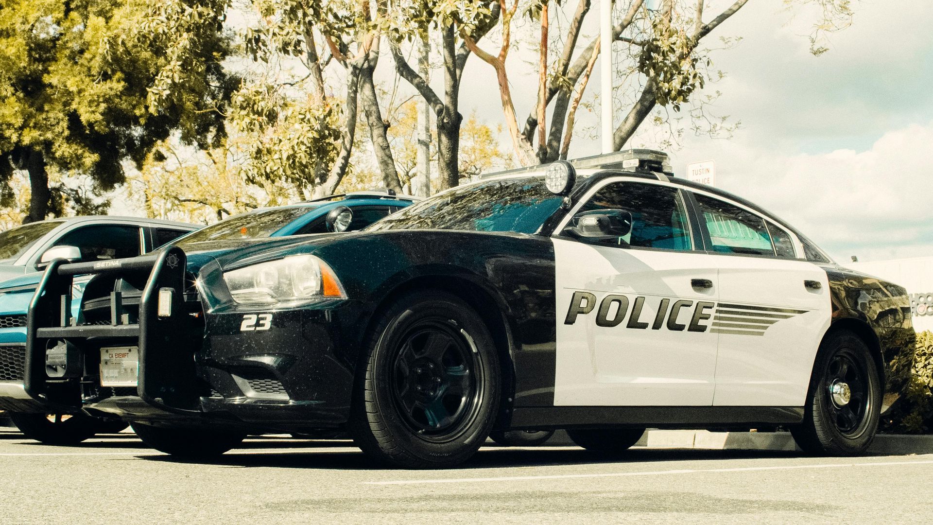 A black-and-white police cruiser parked in an outdoor lot with a bull bar on its front bumper.