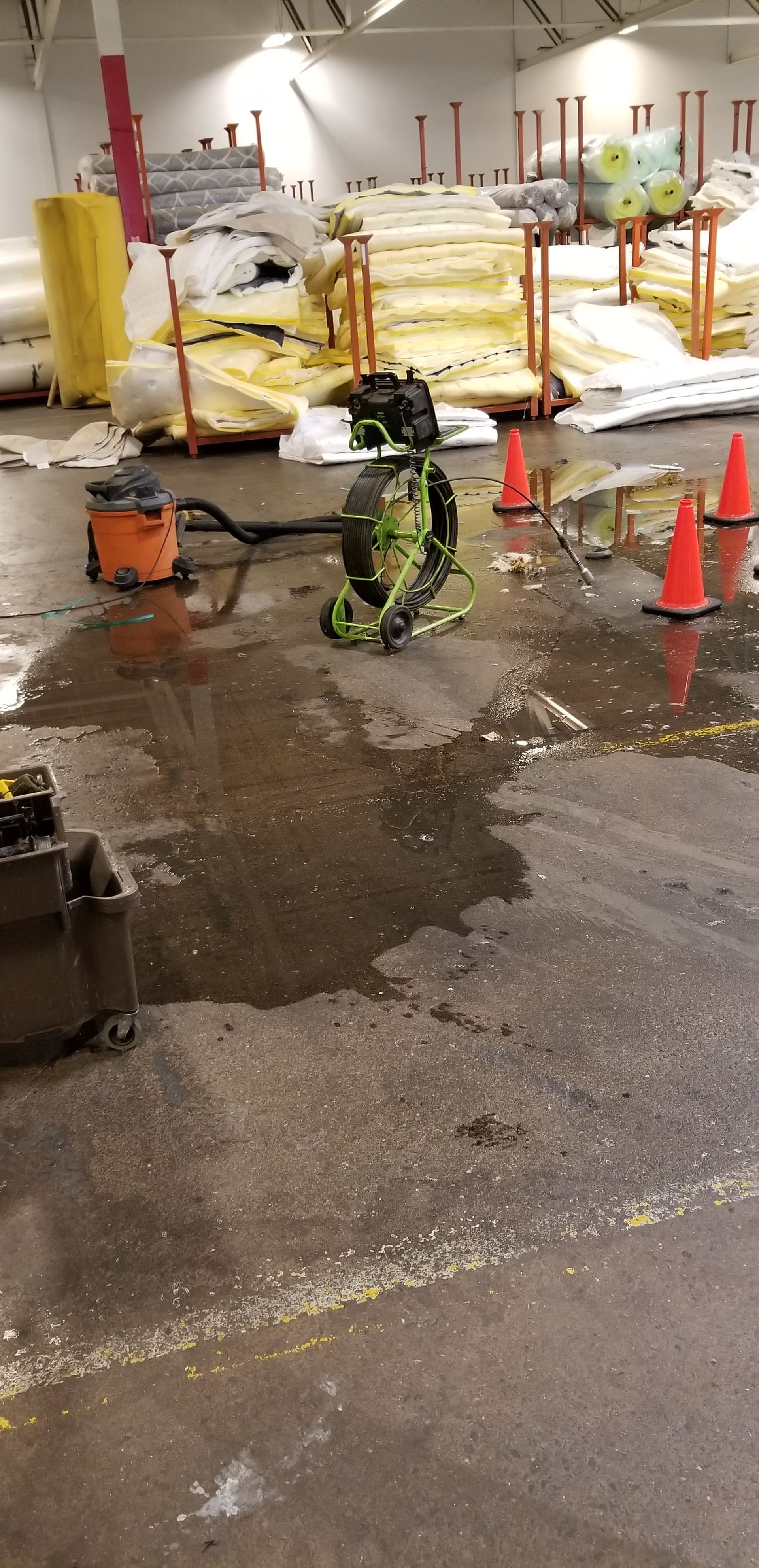 A warehouse with a lot of tables and cones on the floor.