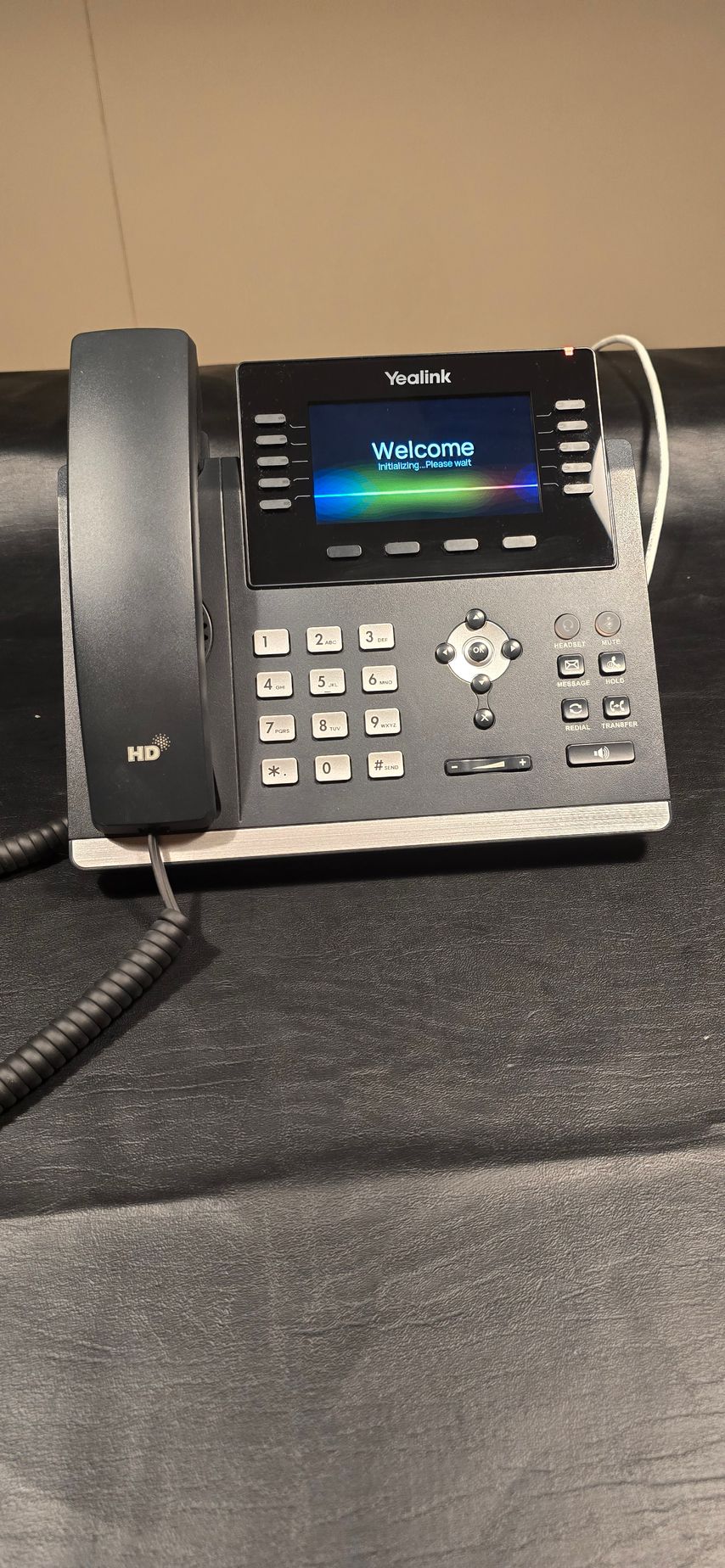A black telephone is sitting on top of a black table.