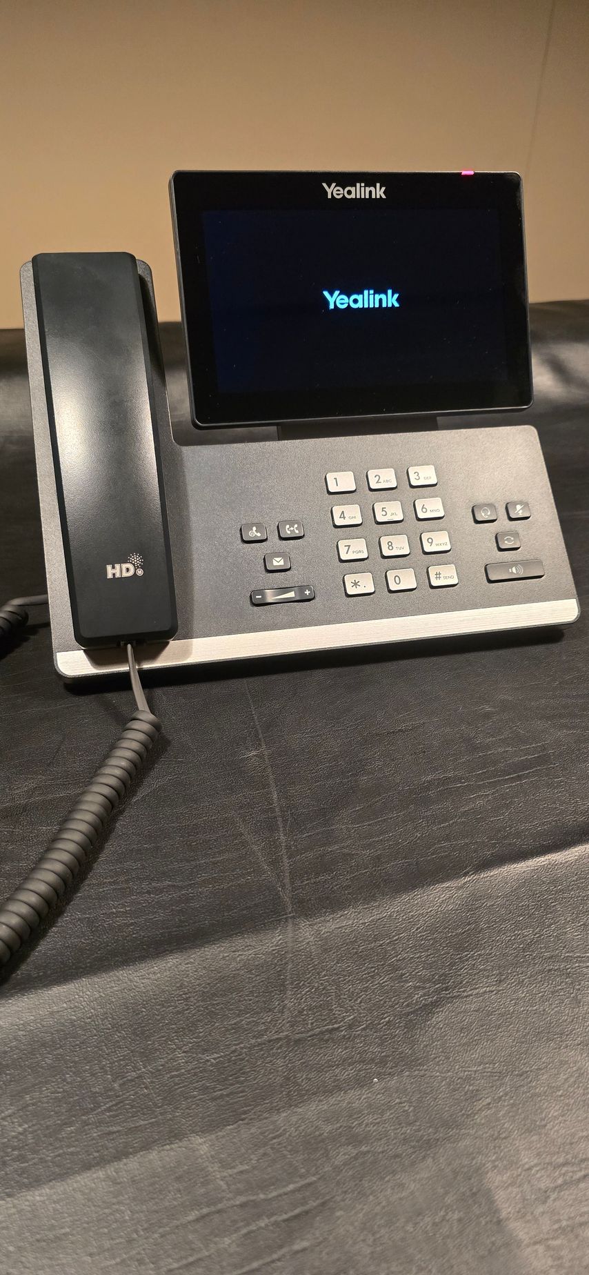 A telephone with a screen on top of it is sitting on a table.