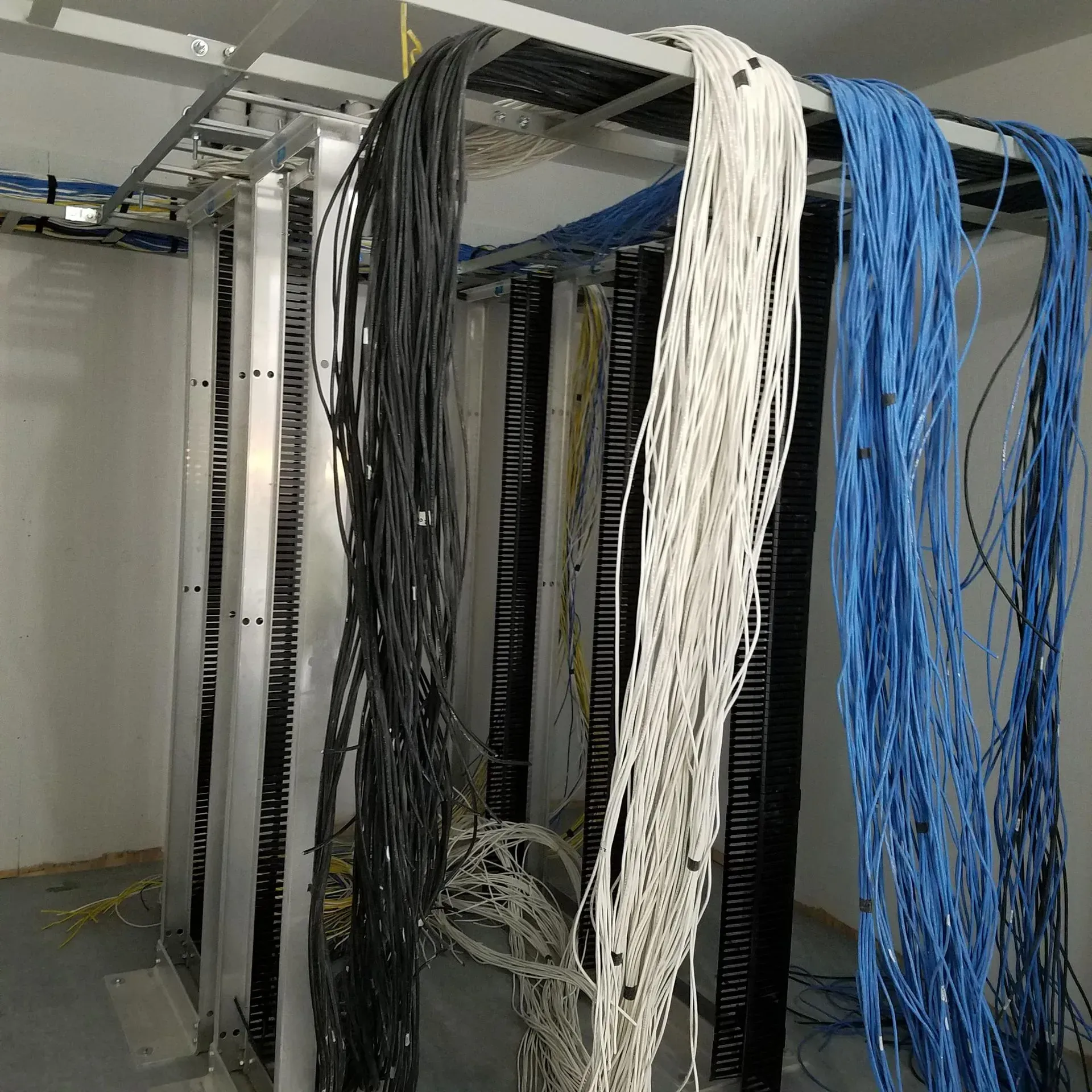 A bunch of wires are hanging from a rack in a room