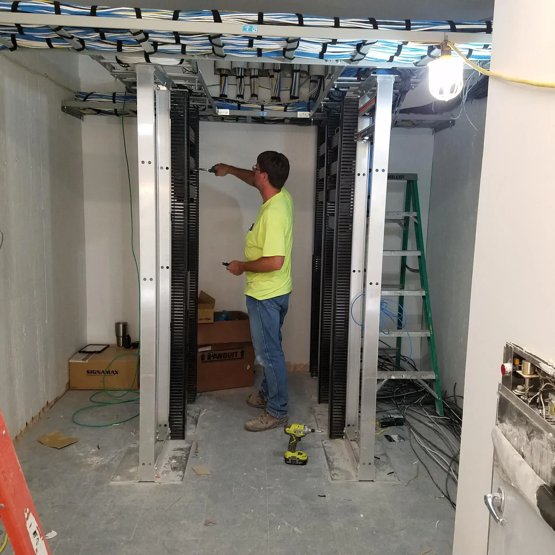A man in a yellow shirt is working on a server rack
