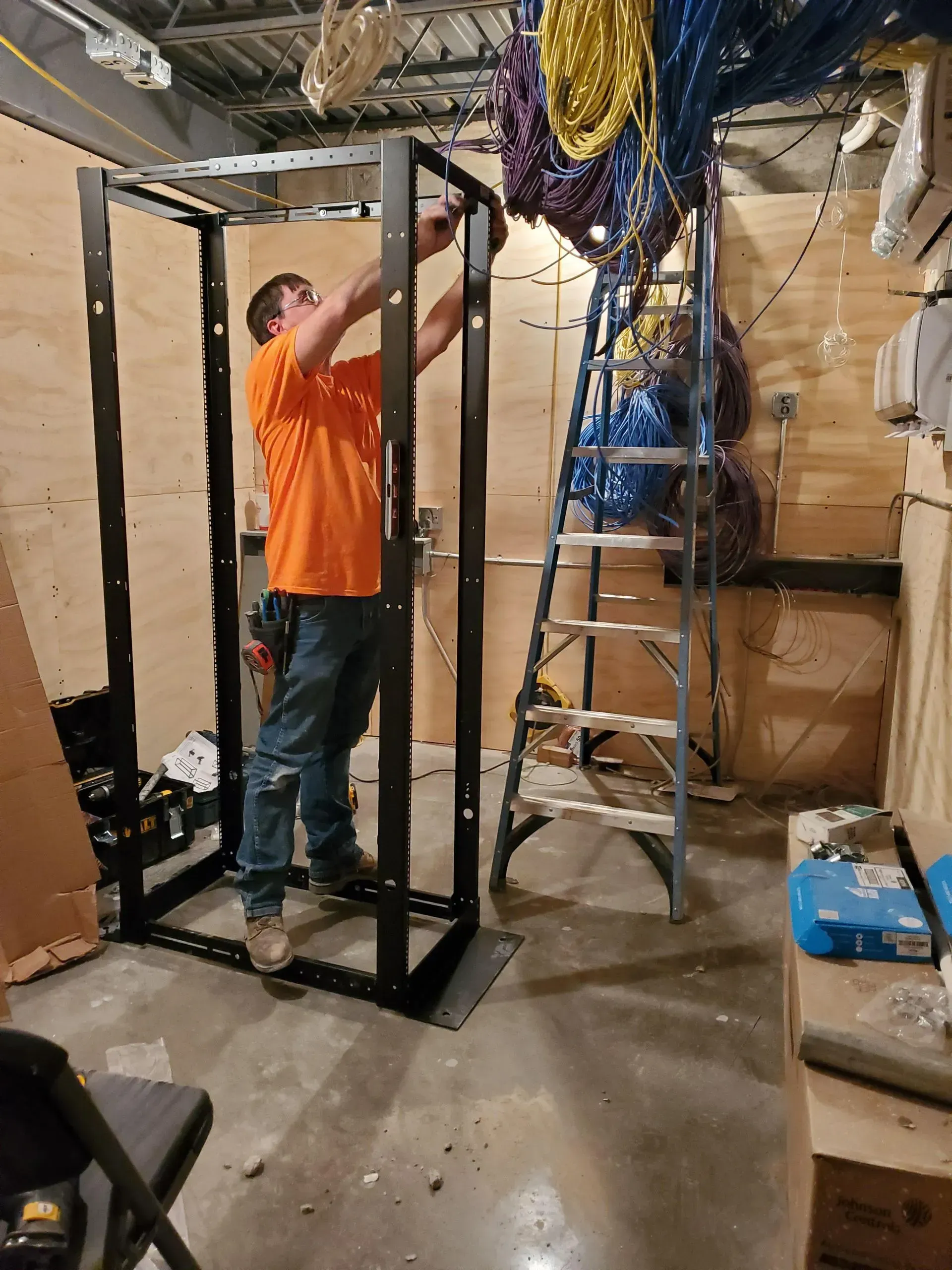 A man is working on a rack in a room with a ladder.