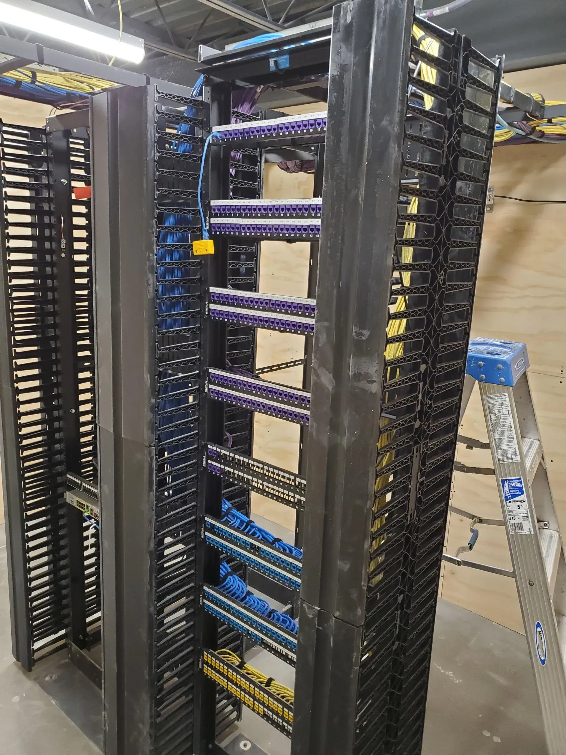 A ladder is sitting next to a rack of wires in a room.