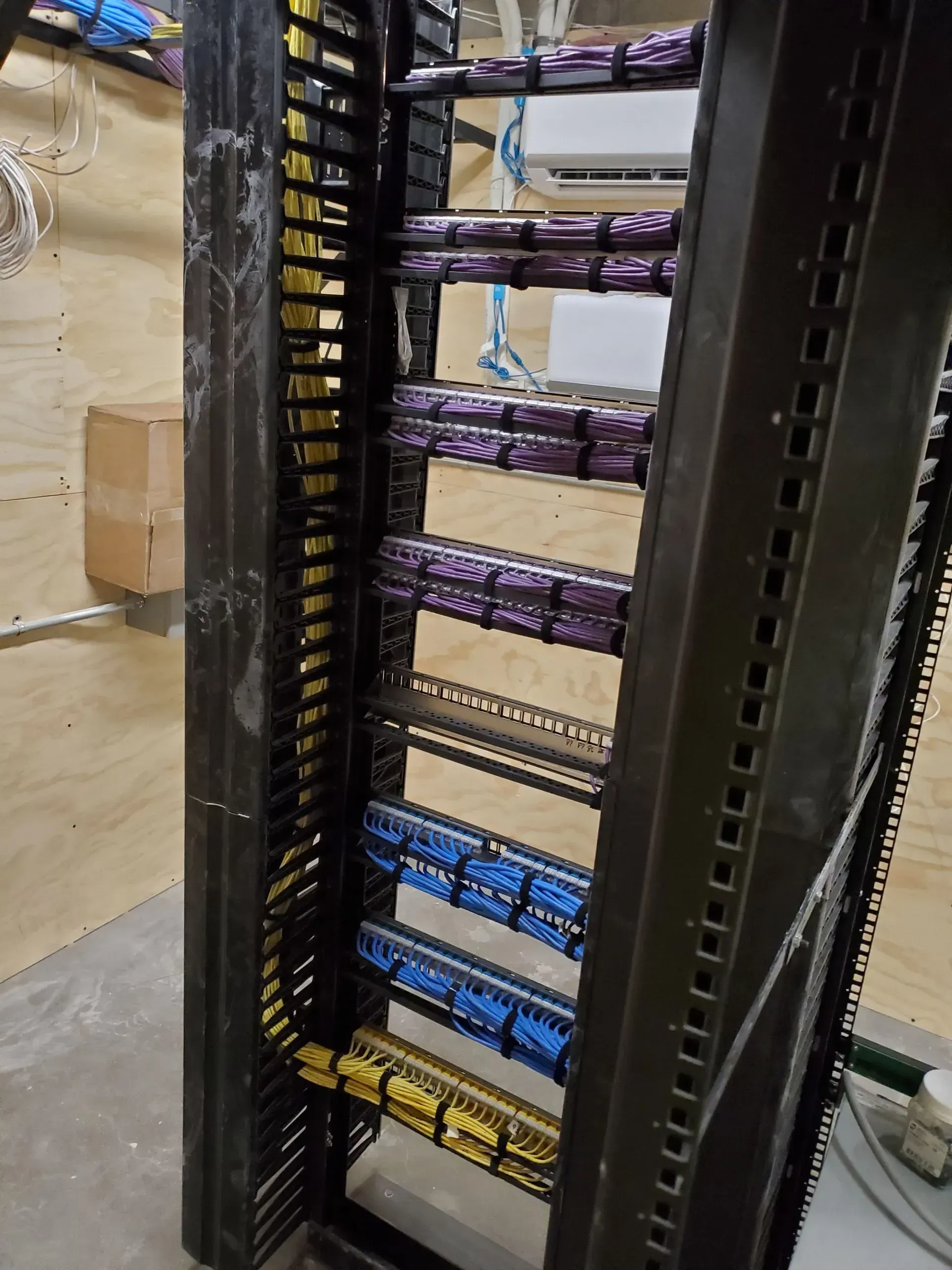 A rack with a lot of wires in it is sitting on a wooden floor.