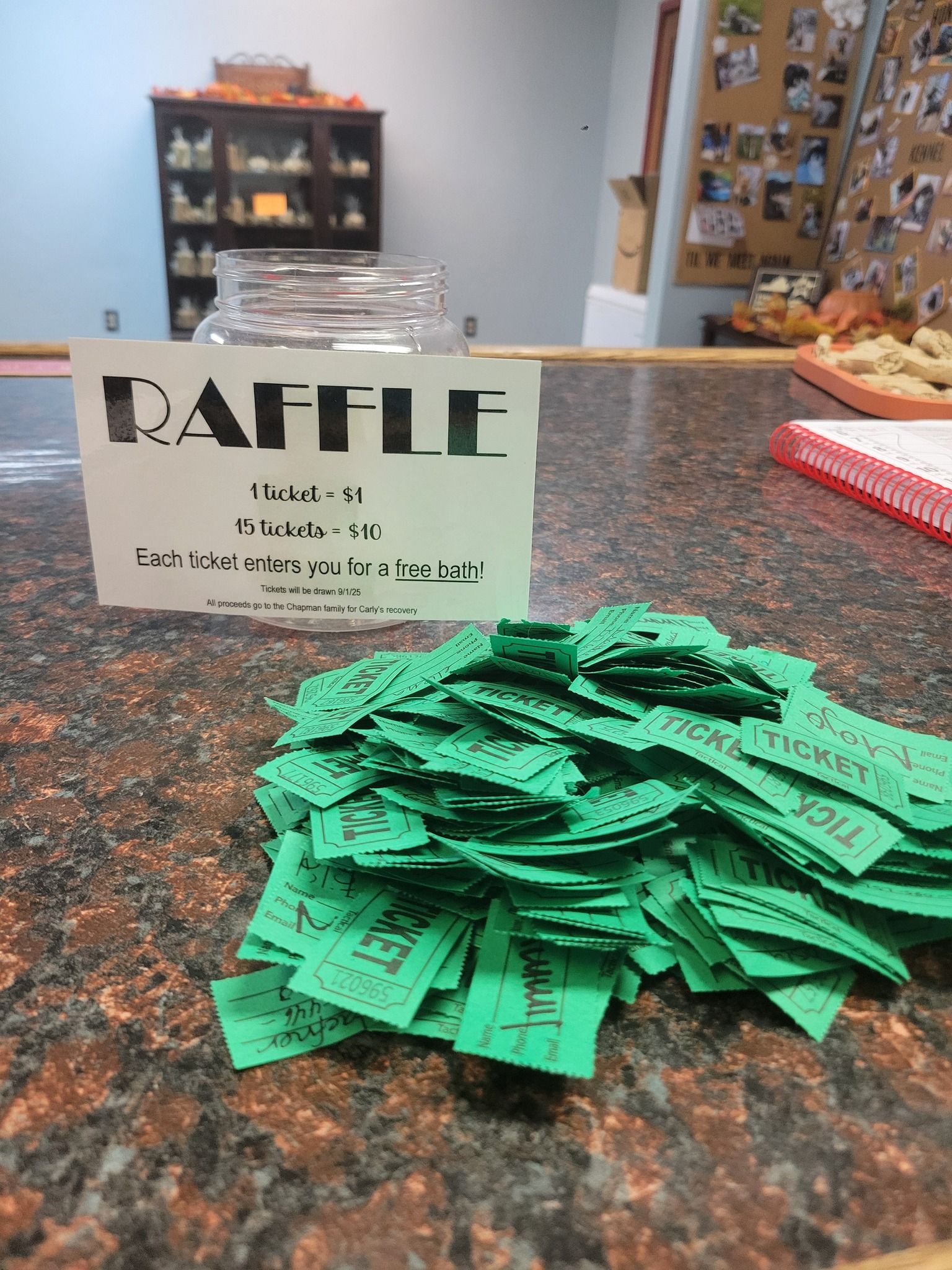 A raffle with green tickets, a glass jar, and a sign on a counter.