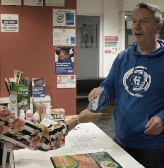 A man in a blue hoodie is standing at a counter