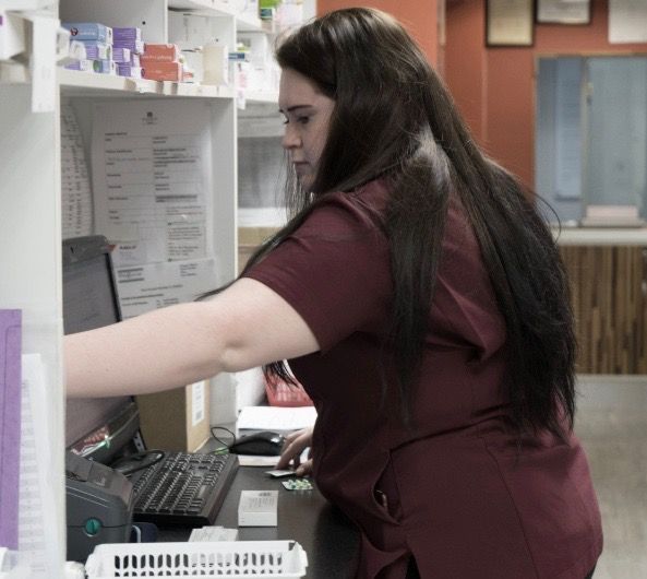A woman is working at a desk in a pharmacy