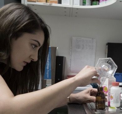 A woman is pouring liquid into a small bottle