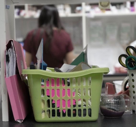 A green laundry basket filled with papers and scissors