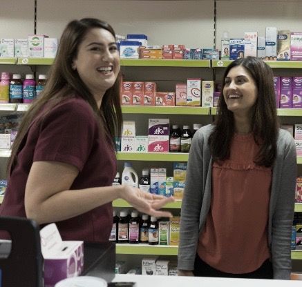 Two women are standing in a pharmacy talking to each other