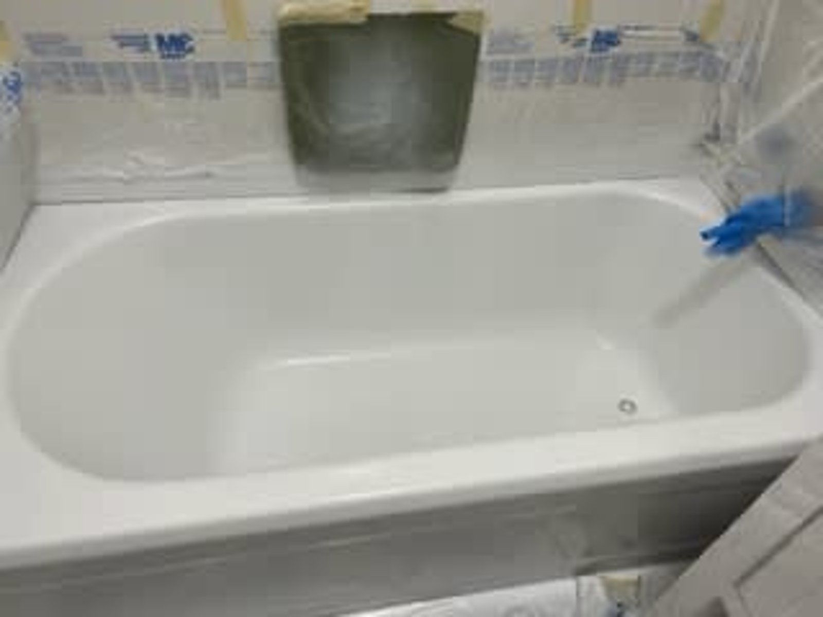 A white bathtub is being painted in a bathroom