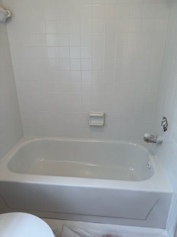 A white bathtub in a bathroom next to a toilet
