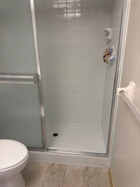 A bathroom with a toilet and a shower with a glass door