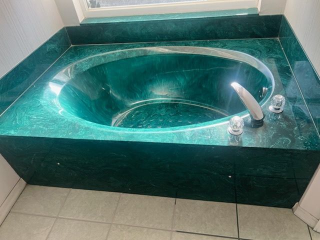 A green bathtub in a bathroom with a window