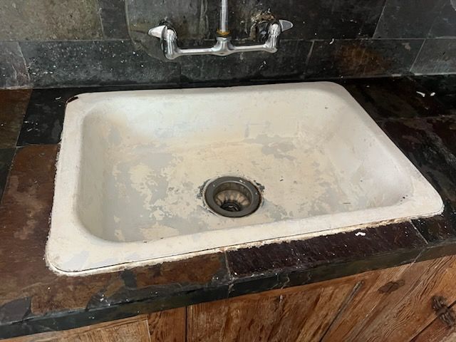 A white sink is sitting on top of a wooden counter