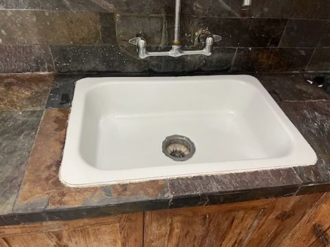 A white sink is sitting on top of a wooden counter