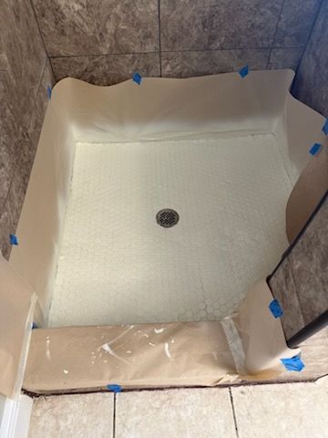 A shower stall is being painted in a bathroom