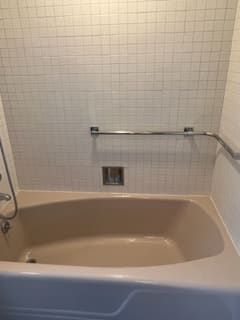 A bathtub with a handle on the side of it in a bathroom