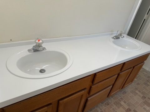 A bathroom counter with two sinks and wooden cabinets