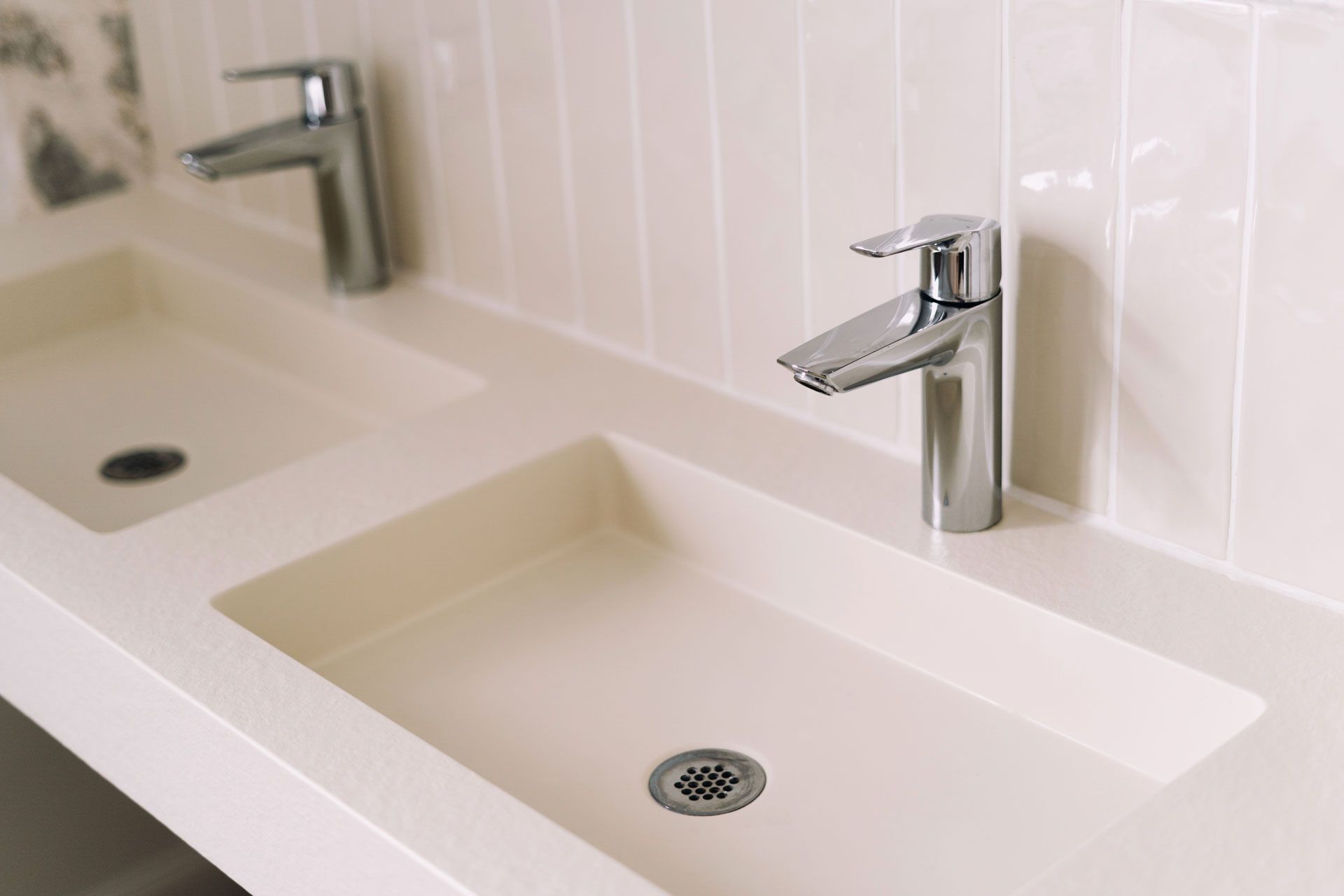 Two white rectangular sinks with chrome faucets in a bathroom.