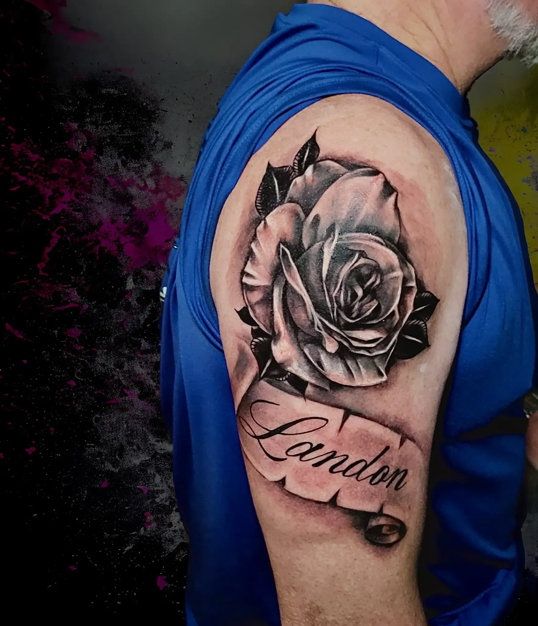 Un hombre tiene un tatuaje de una rosa y el nombre Londres en su brazo.