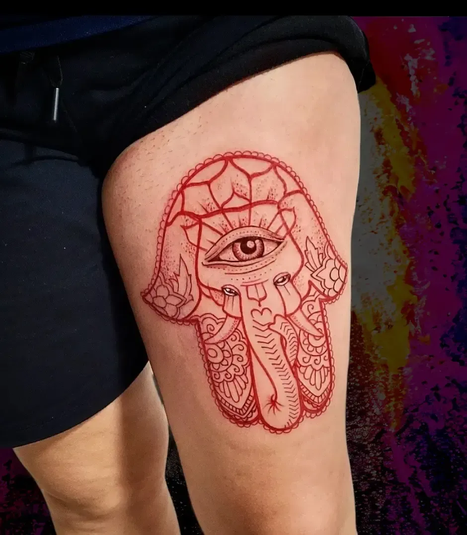 Una mujer tiene un tatuaje de hamsa en el muslo.