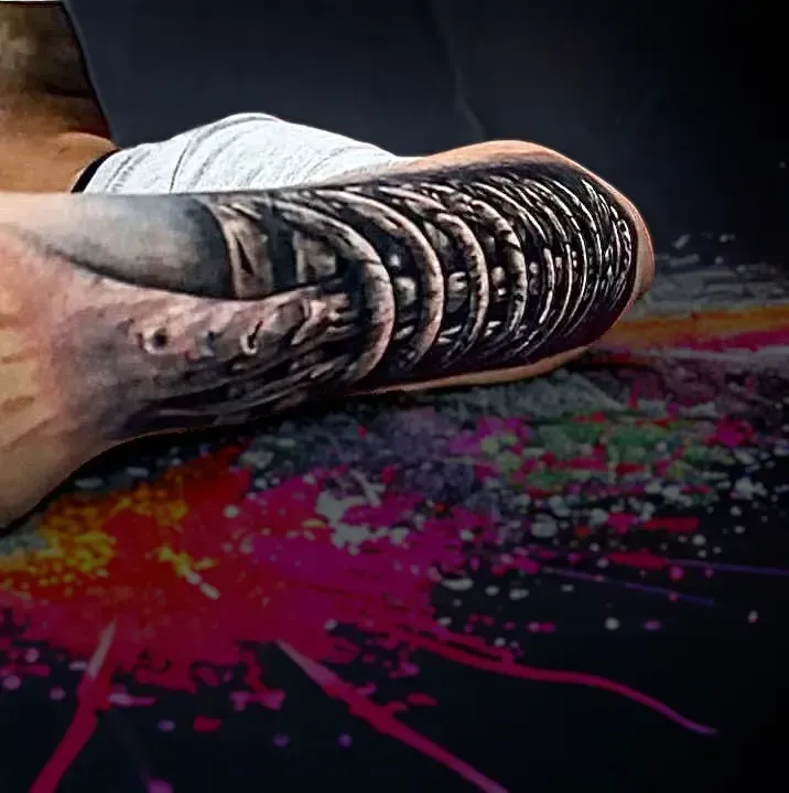 Una persona con un tatuaje en el brazo está tendida en el suelo.