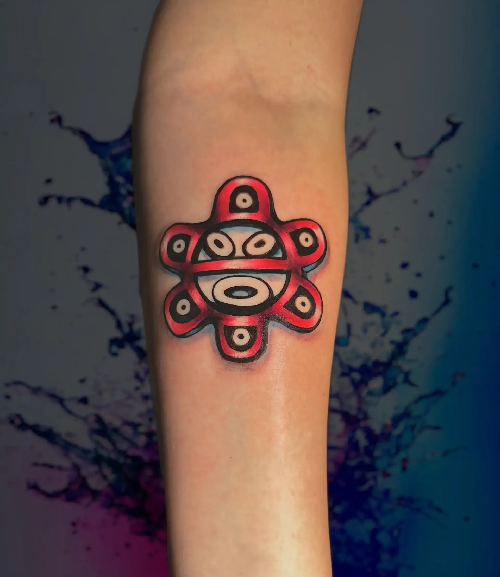 Una persona tiene un tatuaje rojo y negro en el brazo.