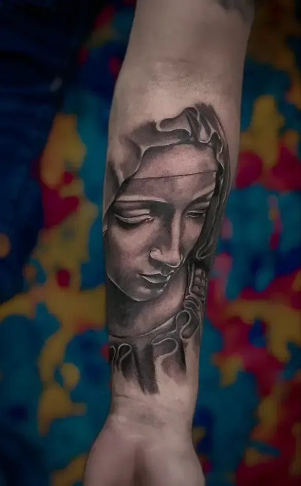 Un tatuaje en blanco y negro de la cara de una mujer en el antebrazo.