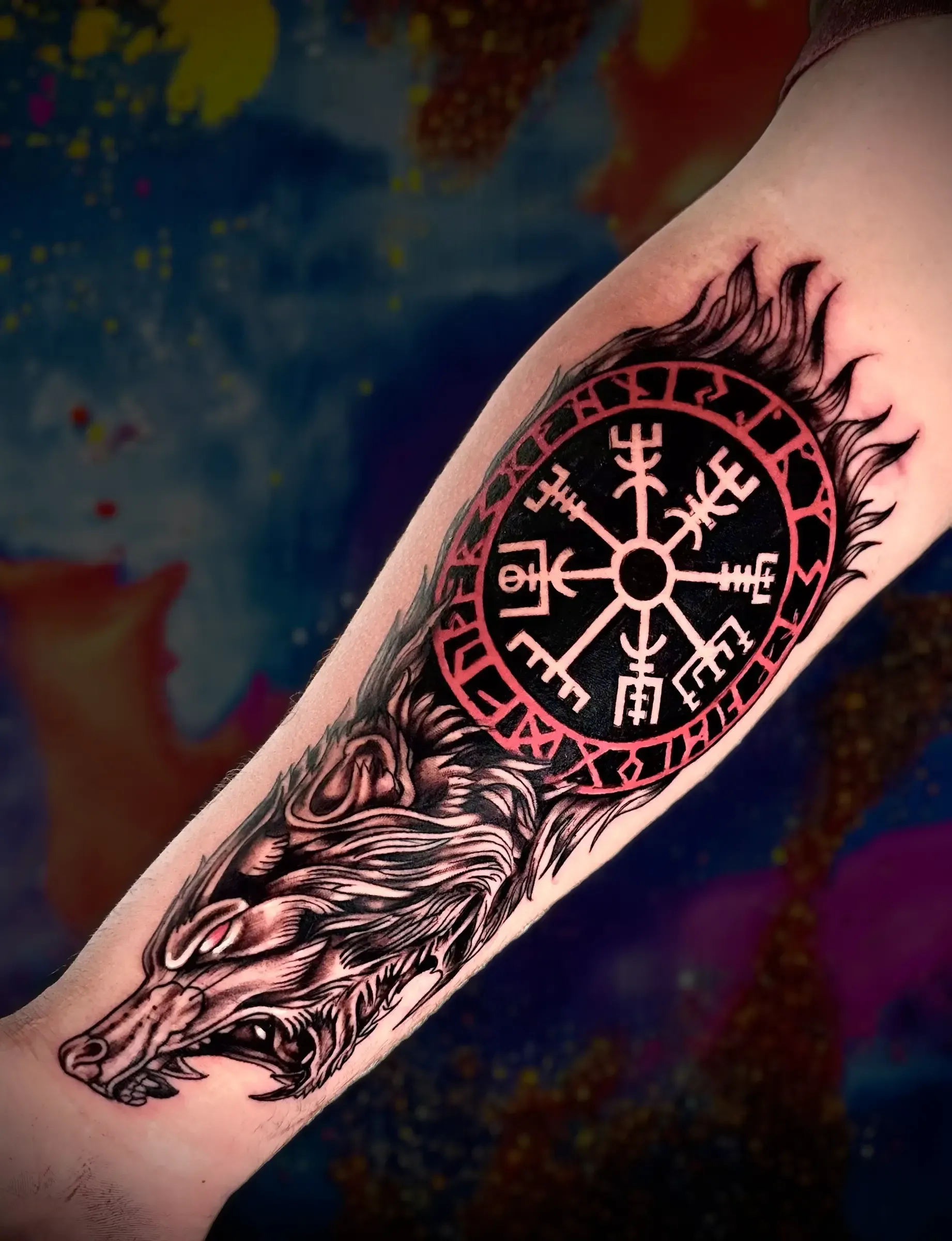 Una persona tiene un tatuaje de un lobo y una brújula en su antebrazo.