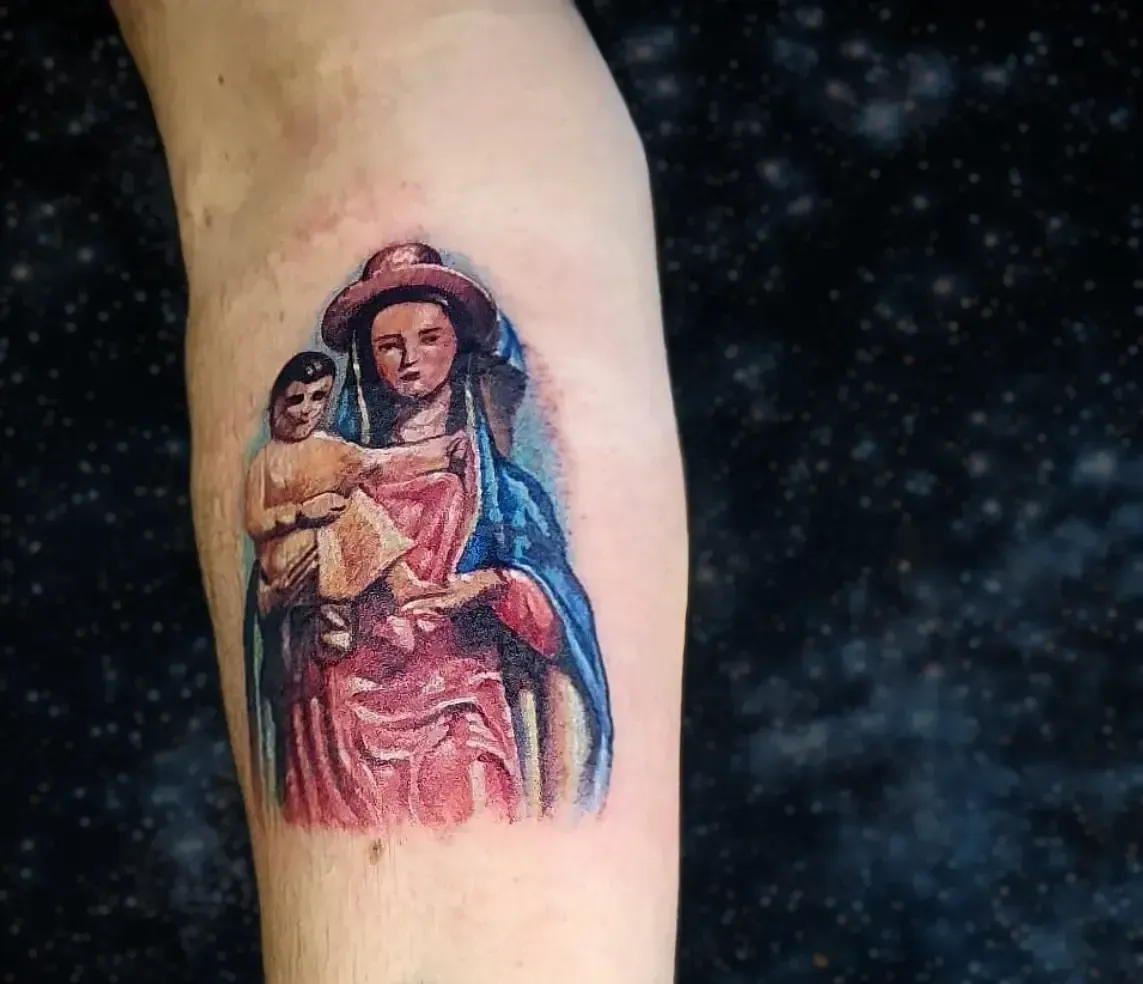 Un tatuaje de una mujer sosteniendo un bebé en una pierna.