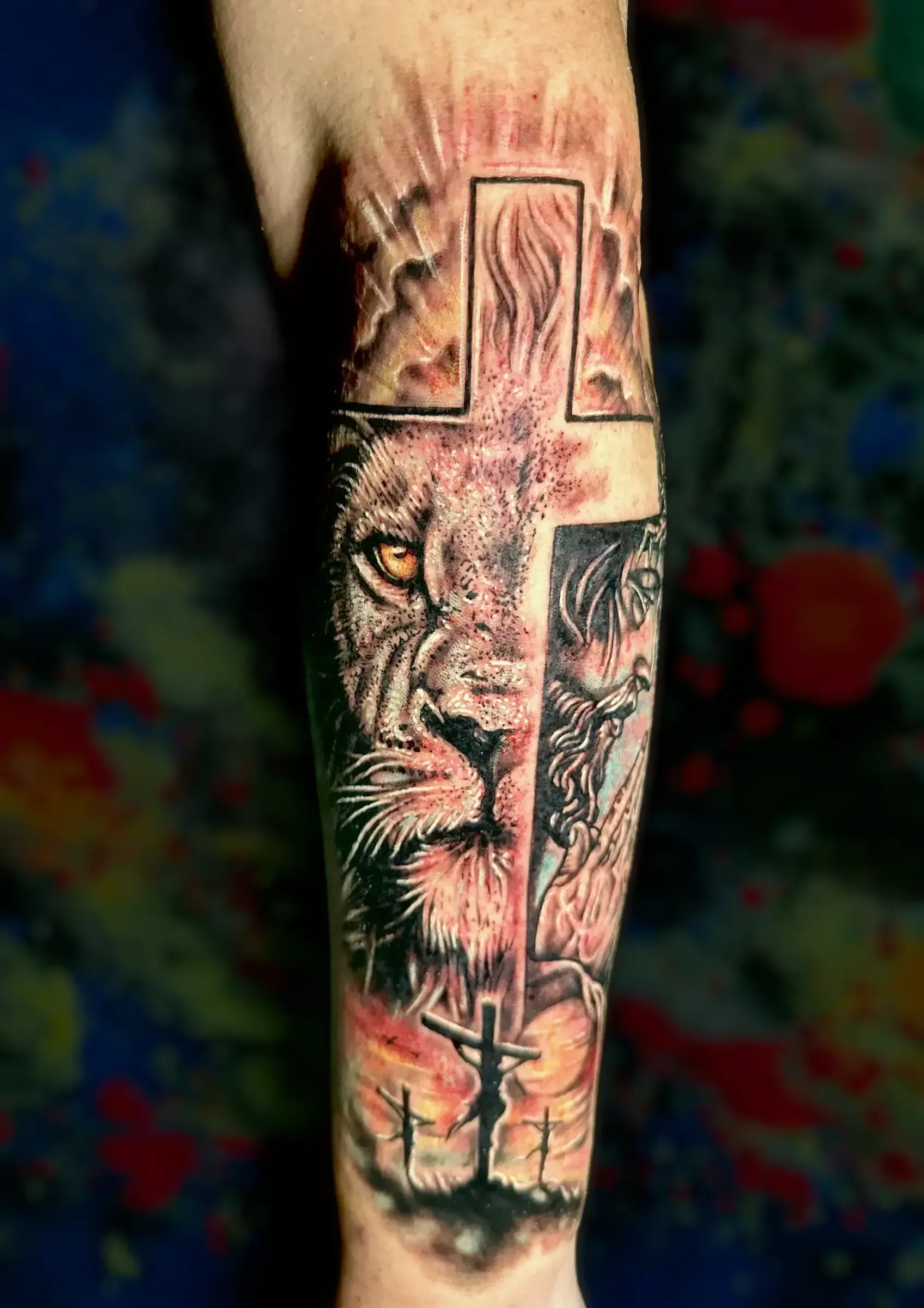 Un tatuaje de un león y una cruz en el antebrazo de una persona.