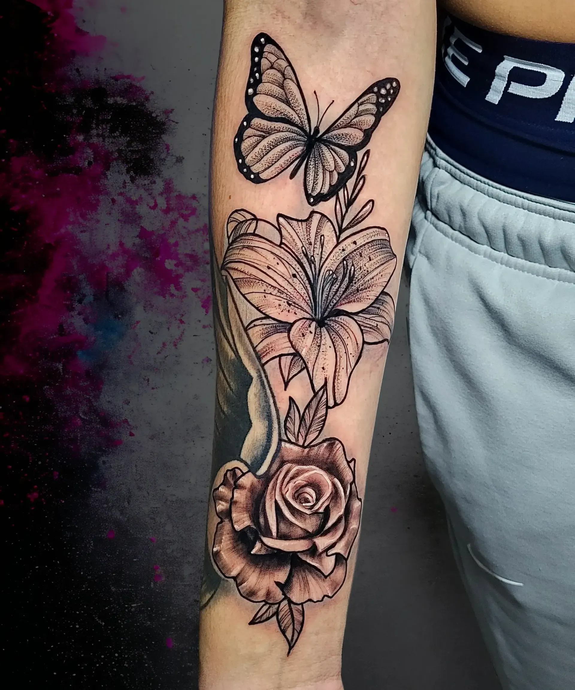 Una persona tiene un tatuaje de una mariposa y una rosa en su antebrazo.