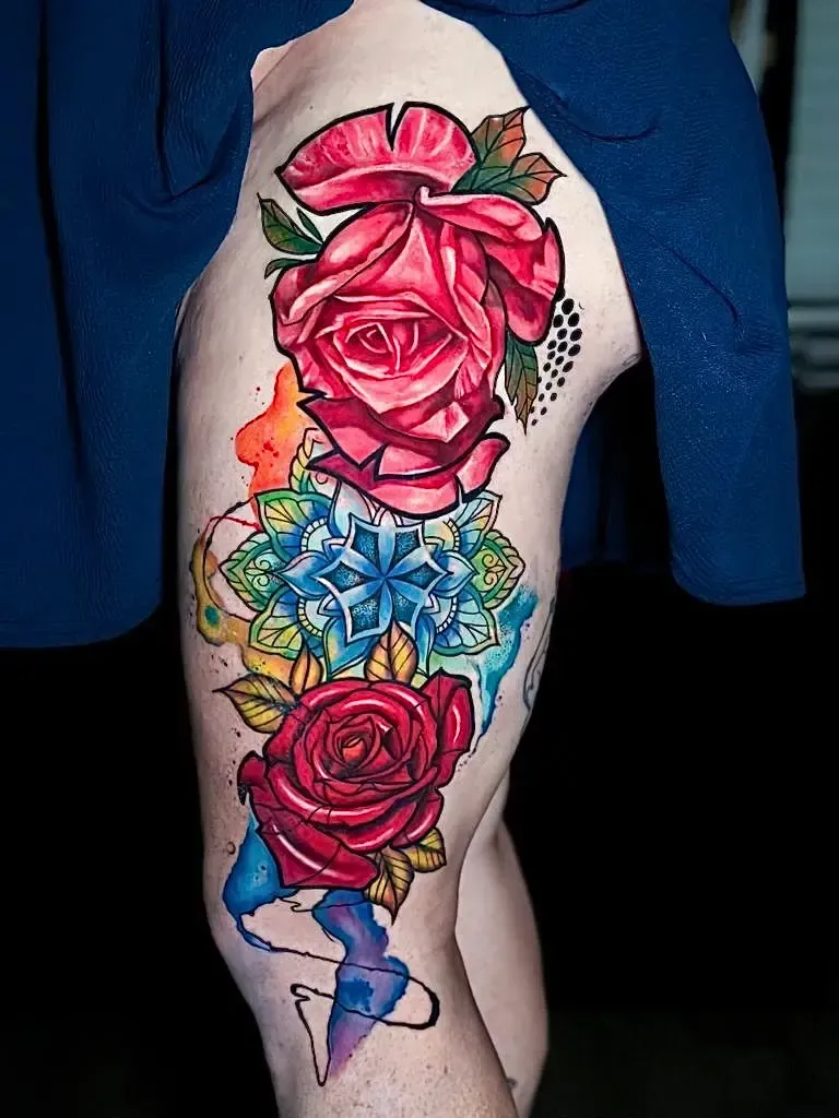 Una persona tiene un tatuaje colorido de rosas y copos de nieve en su pierna.