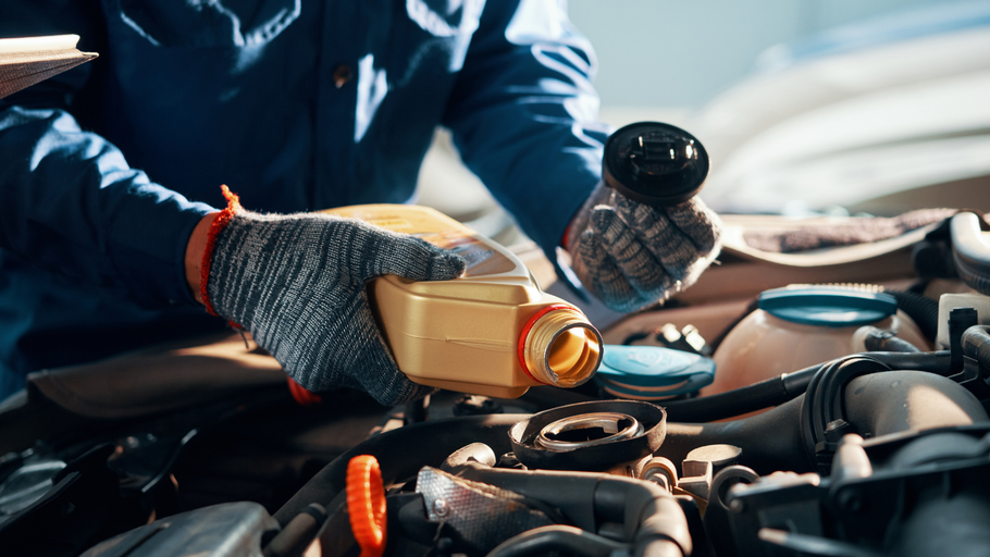 A mechanic is pouring oil into a car engine.