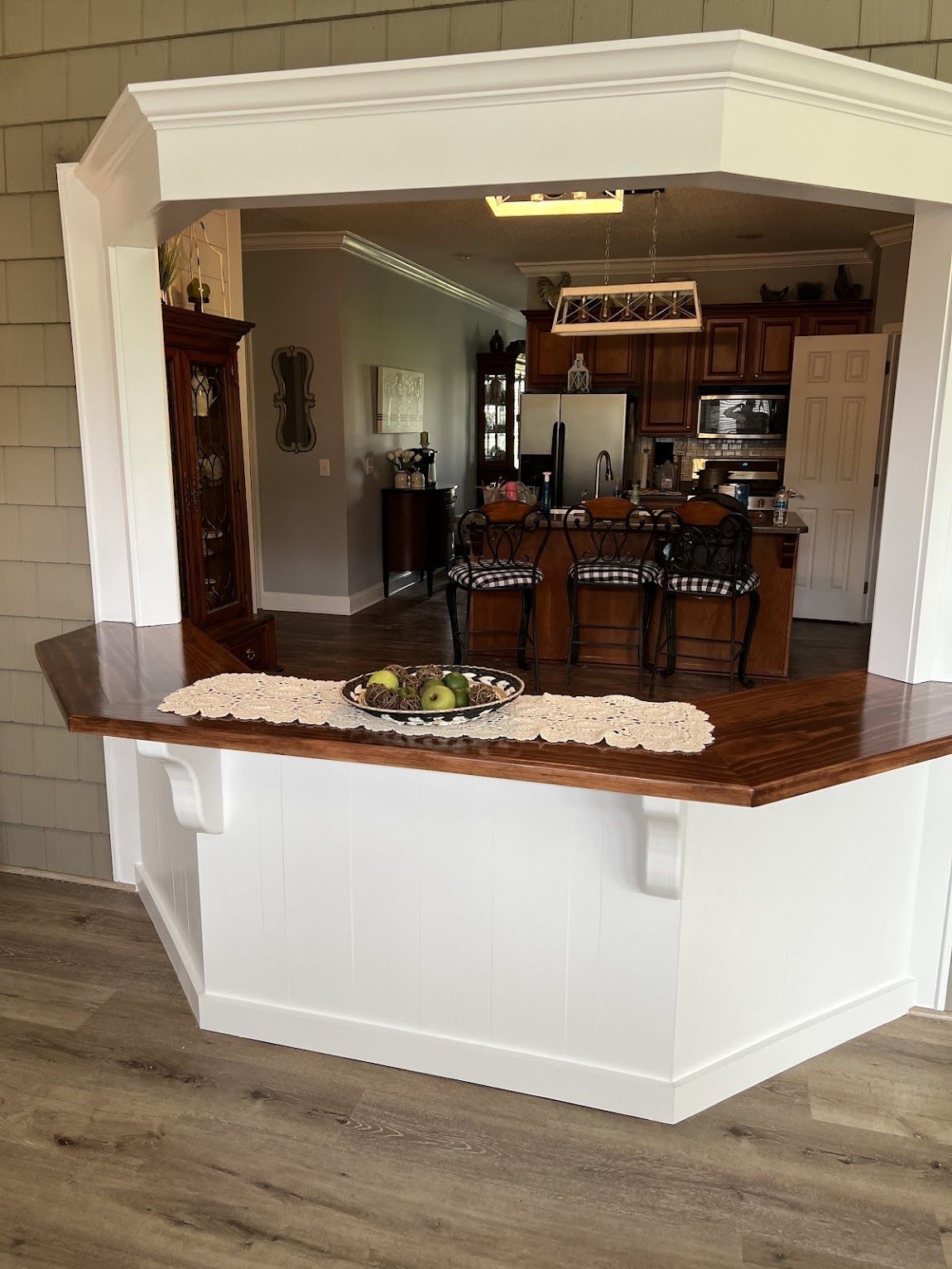 A kitchen pass-through with a wooden countertop and white trim, overlooking a kitchen.