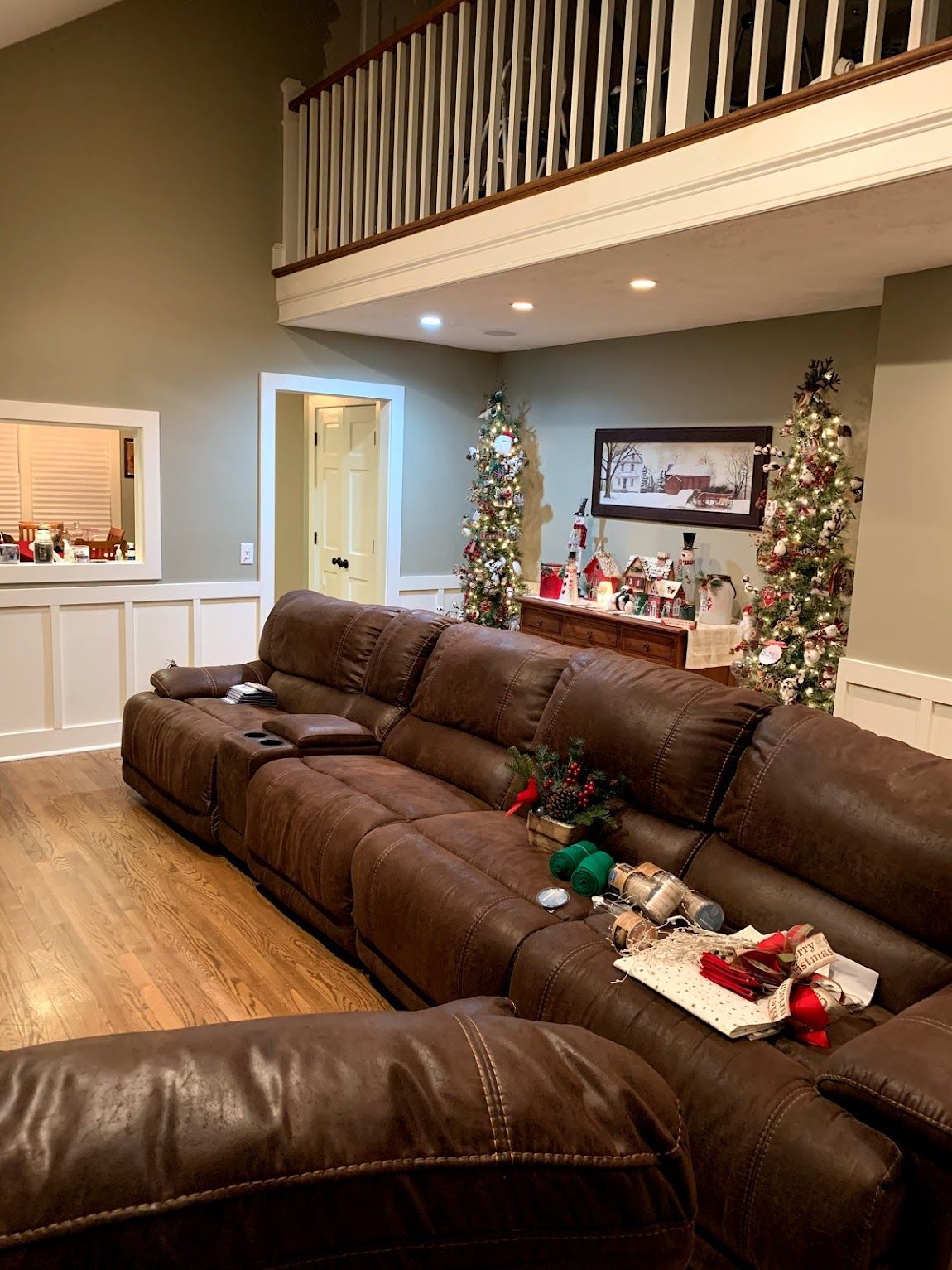 Living room with brown leather sectional sofa, Christmas decorations, and a balcony.