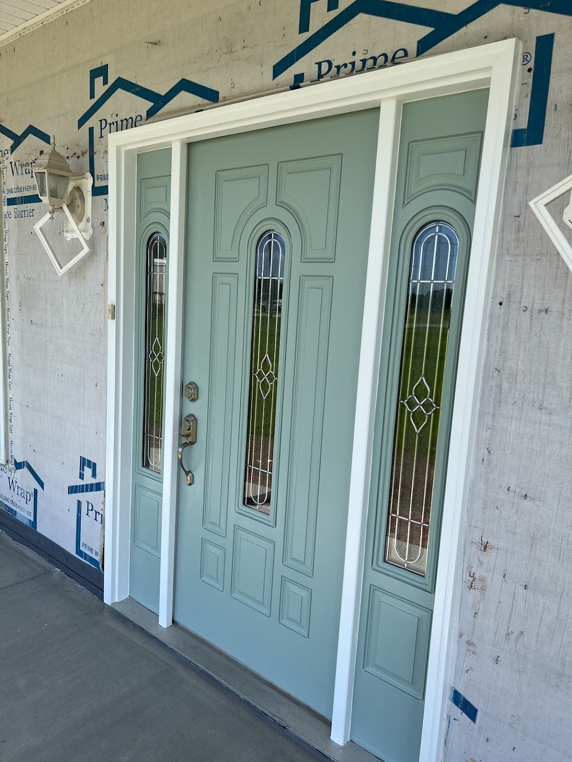 Light blue front door with sidelights, white trim, and a porch.