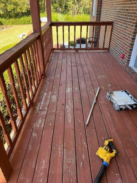Wooden deck with peeling red stain, railings, and painting supplies.