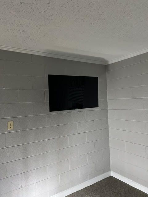 Gray cinder block wall with mounted black television. White trim.