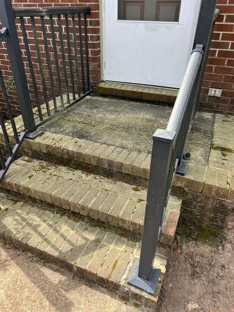 Brick steps leading to a white door, framed by a black railing.