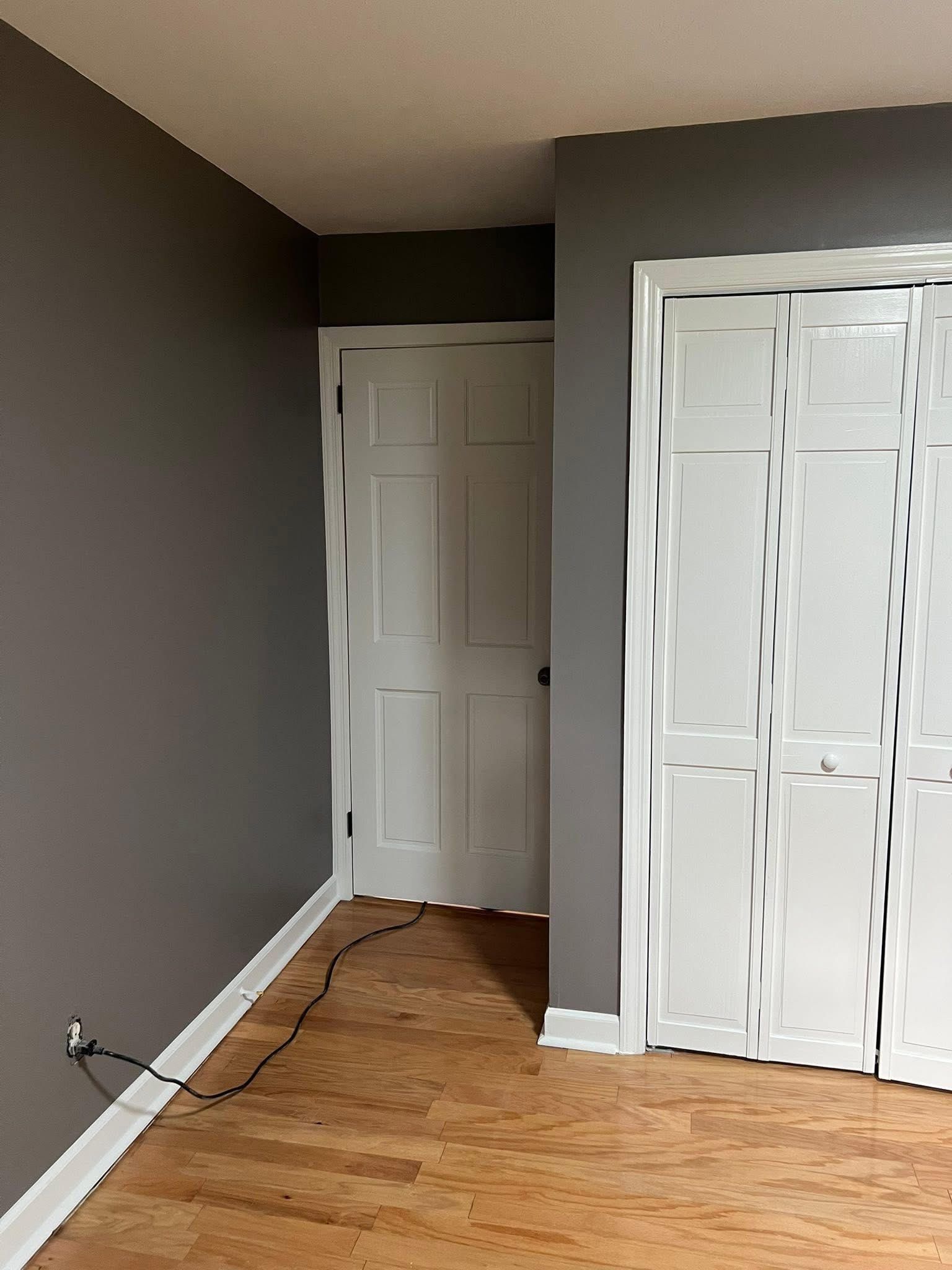Gray-walled room with white doors and closet. Wooden floor and white trim.